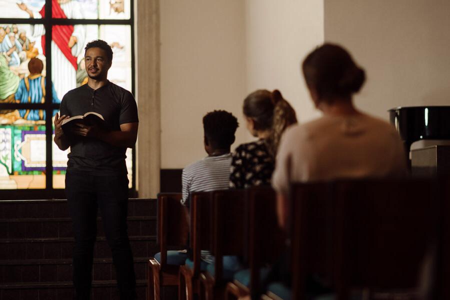 Student reads the bible at the front of chapel.